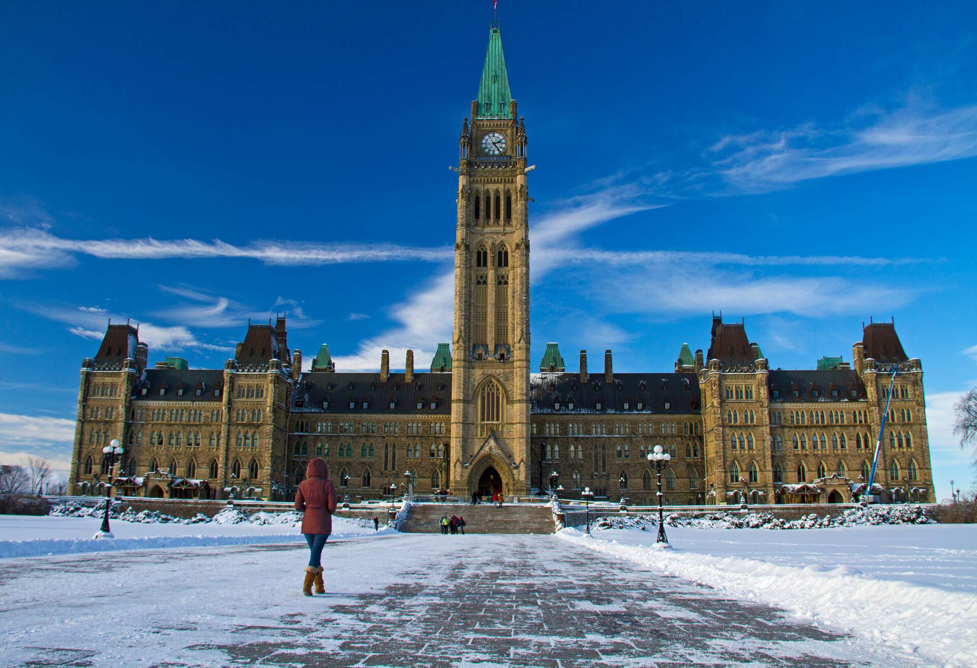 A woman bundled up in winter clothes walks in front of the Canadian Parliament Building during a cold winter day in Ottawa, Ontario