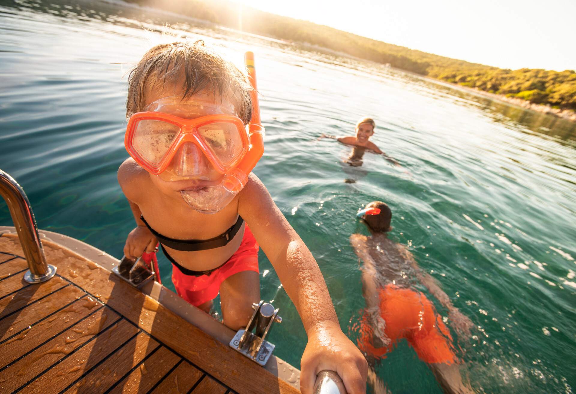 Caucasian boy wearing swimming goggles and snorkel joining family in the sea from boat, Croatia