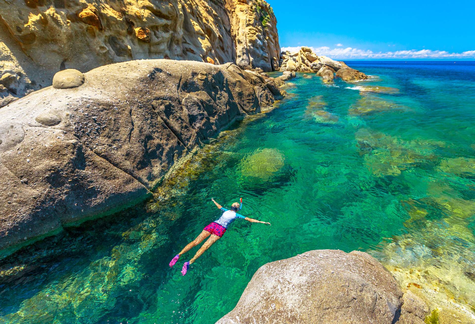 Top view of snorkeler in Sant 'Andrea beach with rocks and coves, Elba island, Italy