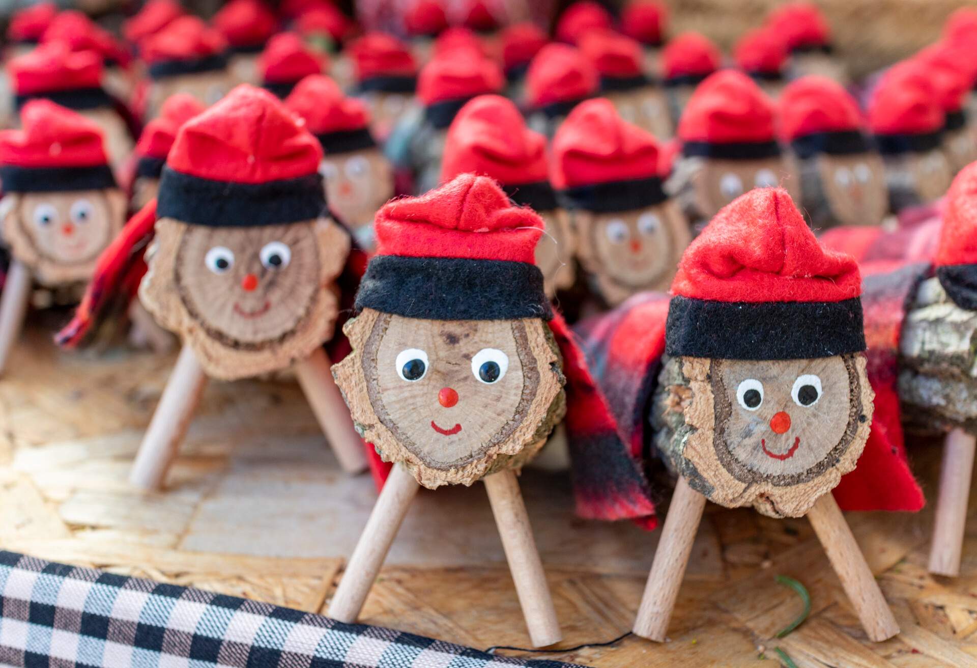 A display of small chopped-up tree trunks decorated with stick stands, smiley faces, and red hats.