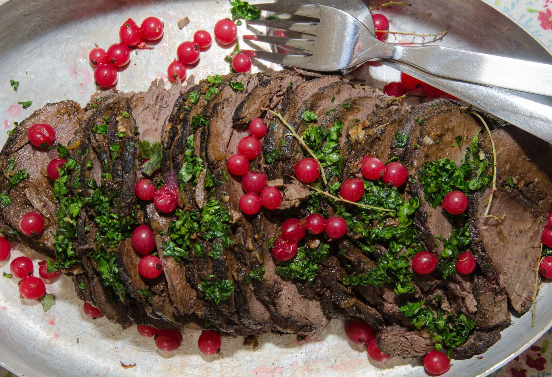 Moose steak ready to serve in form of slices with red currants and parsley