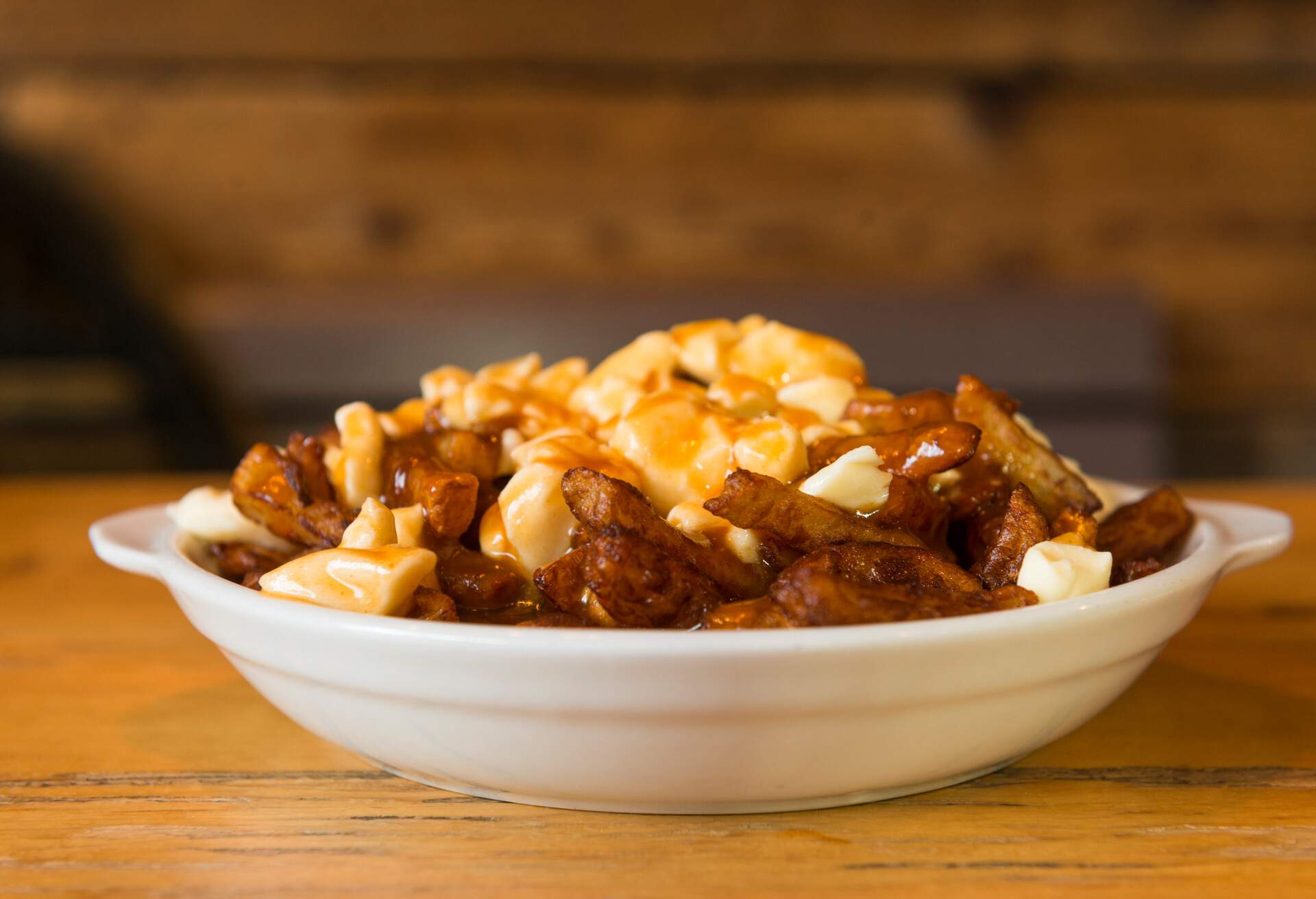 This is a horizontal, color, royalty free stock photograph of a hot full plate of French Canadian cuisine, poutine, which consists of fries, curd cheese, and gravy. Photographed with a Nikon D800.