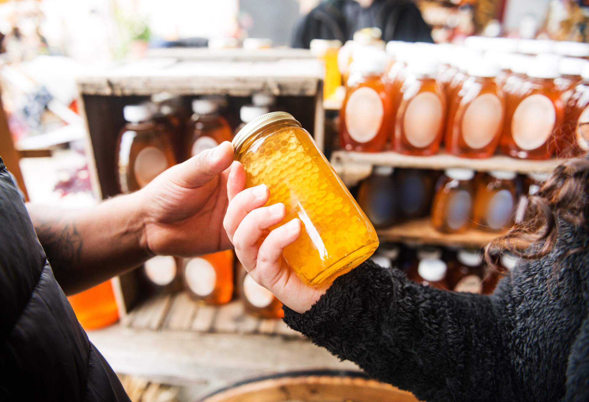 A Hispanic couple in their 20s shops for honey at a farmer’s market in upstate New York.