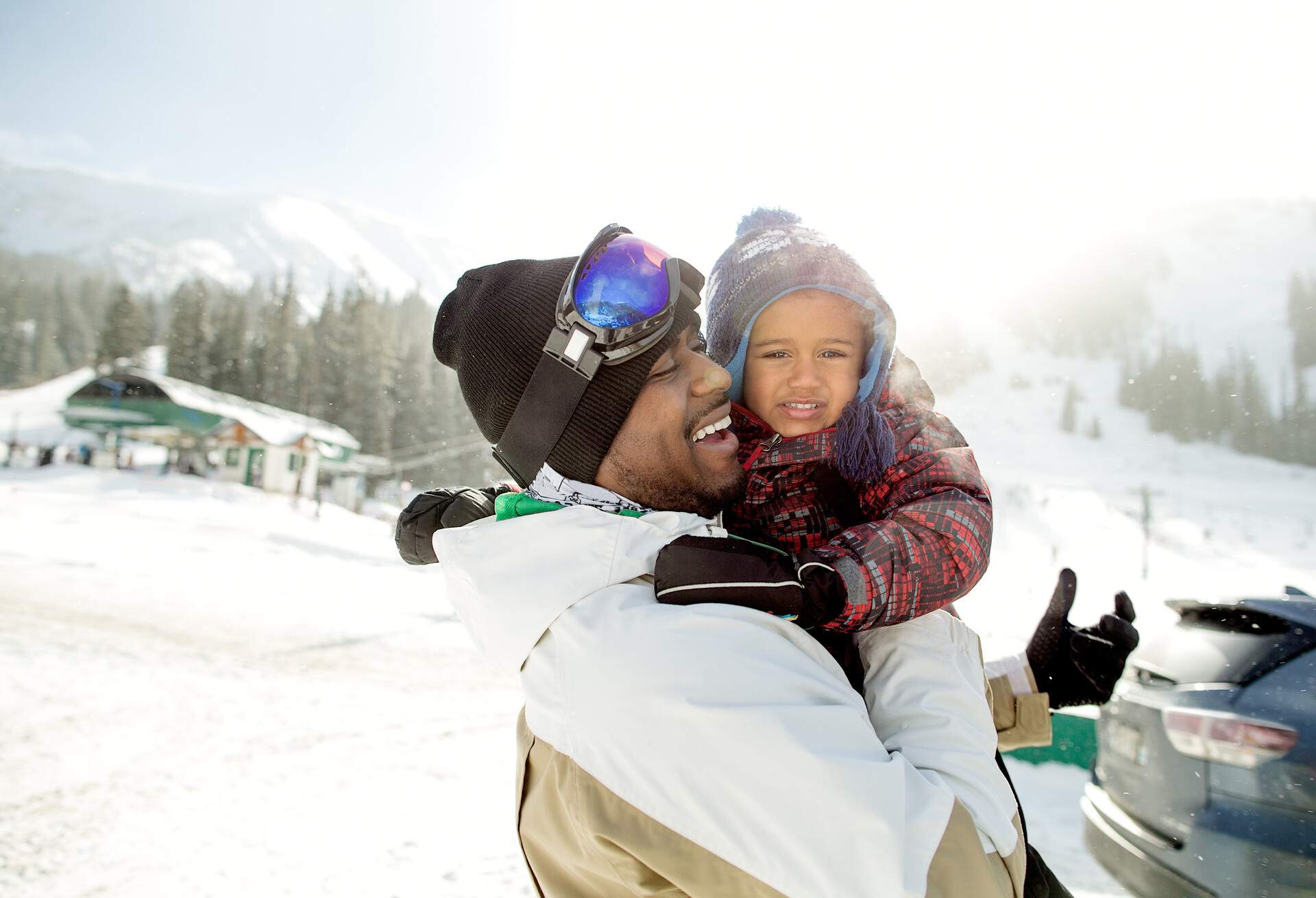 A person and child in winter clothing hug and smile at each other.