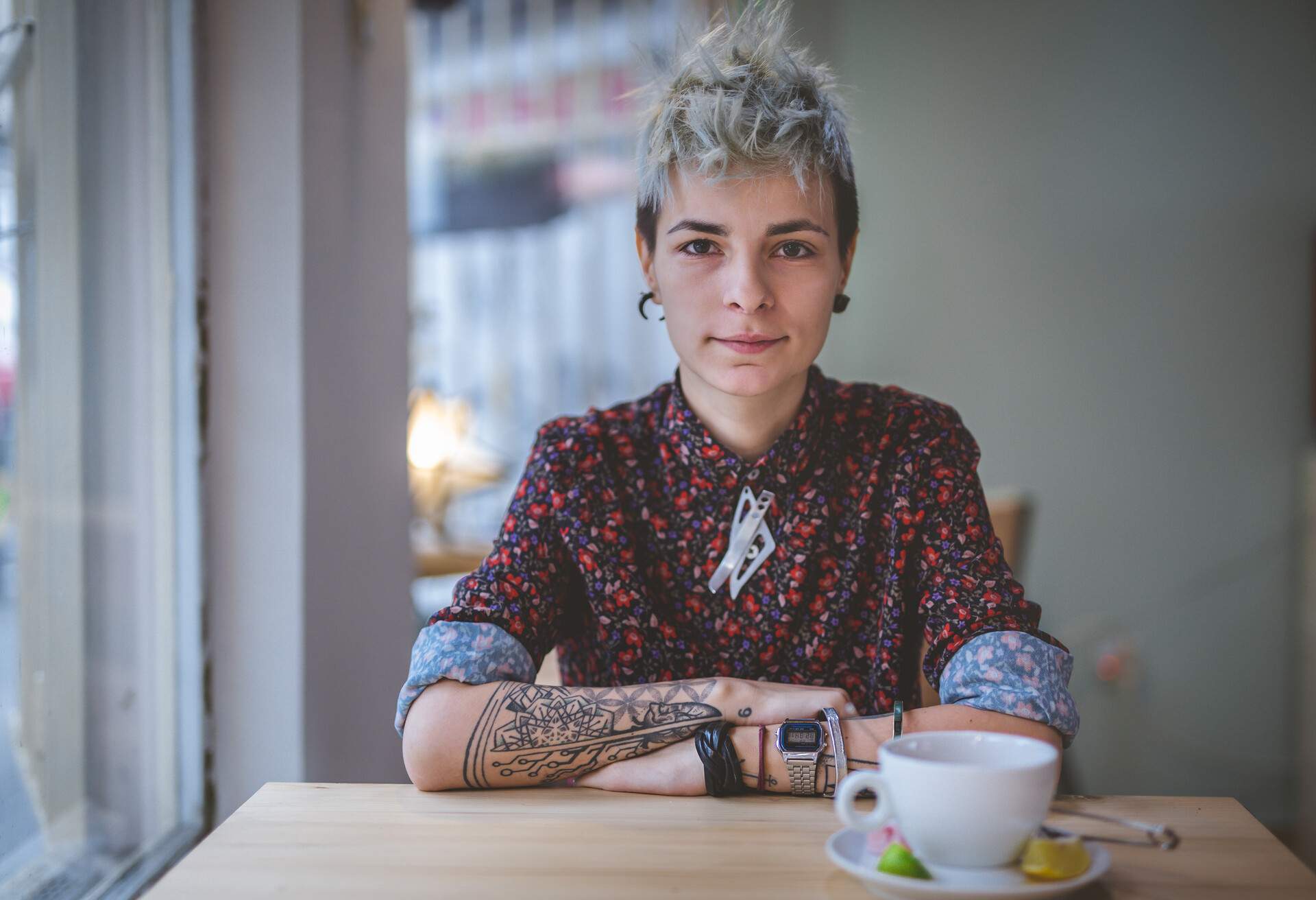 Young and lovely gender blend woman, enjoying a cup of coffee at the cafe.