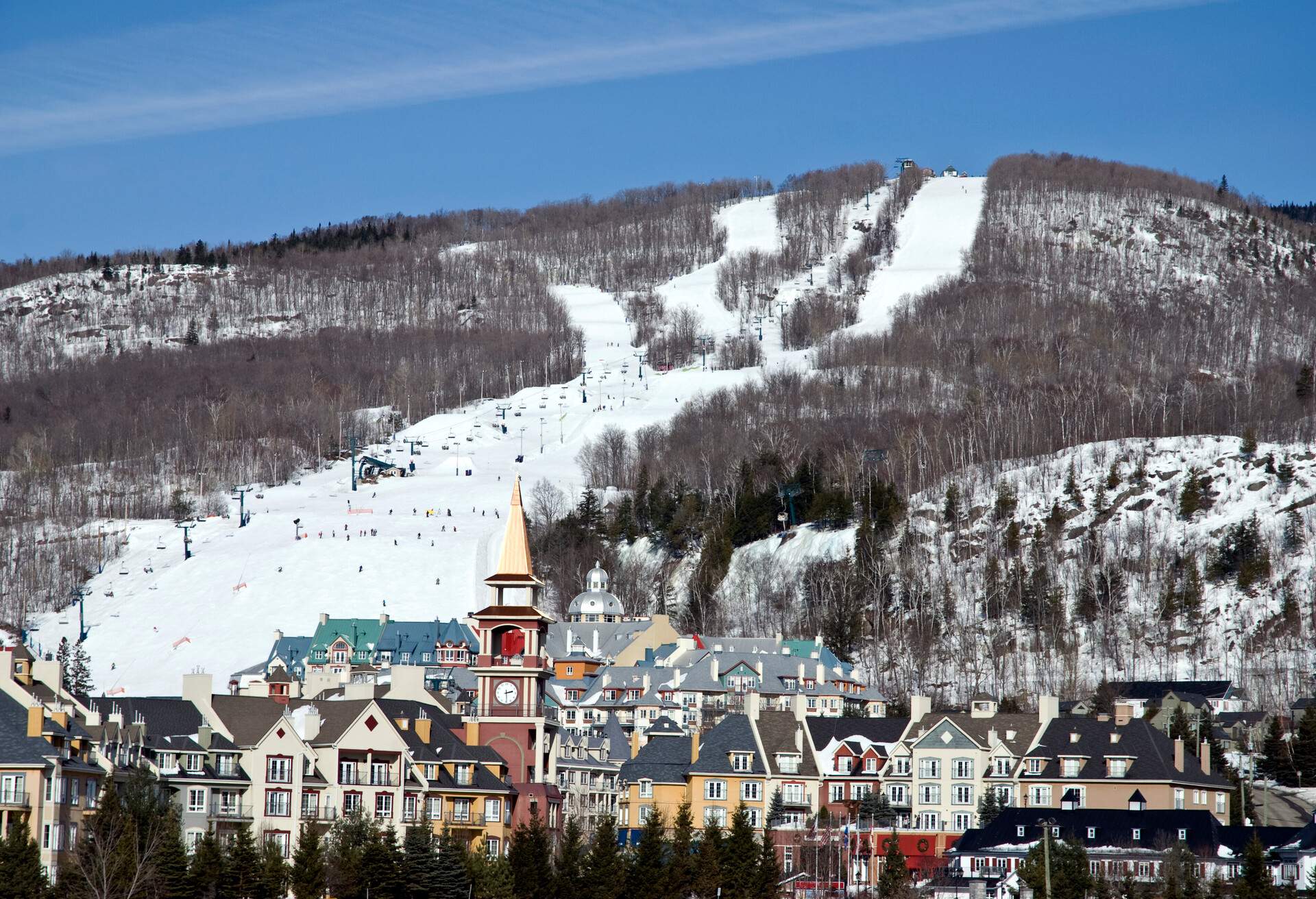 The colourful European-inspired ski resort buildings are nestled beneath the rolling hills of the ski slopes surrounded by bare trees.