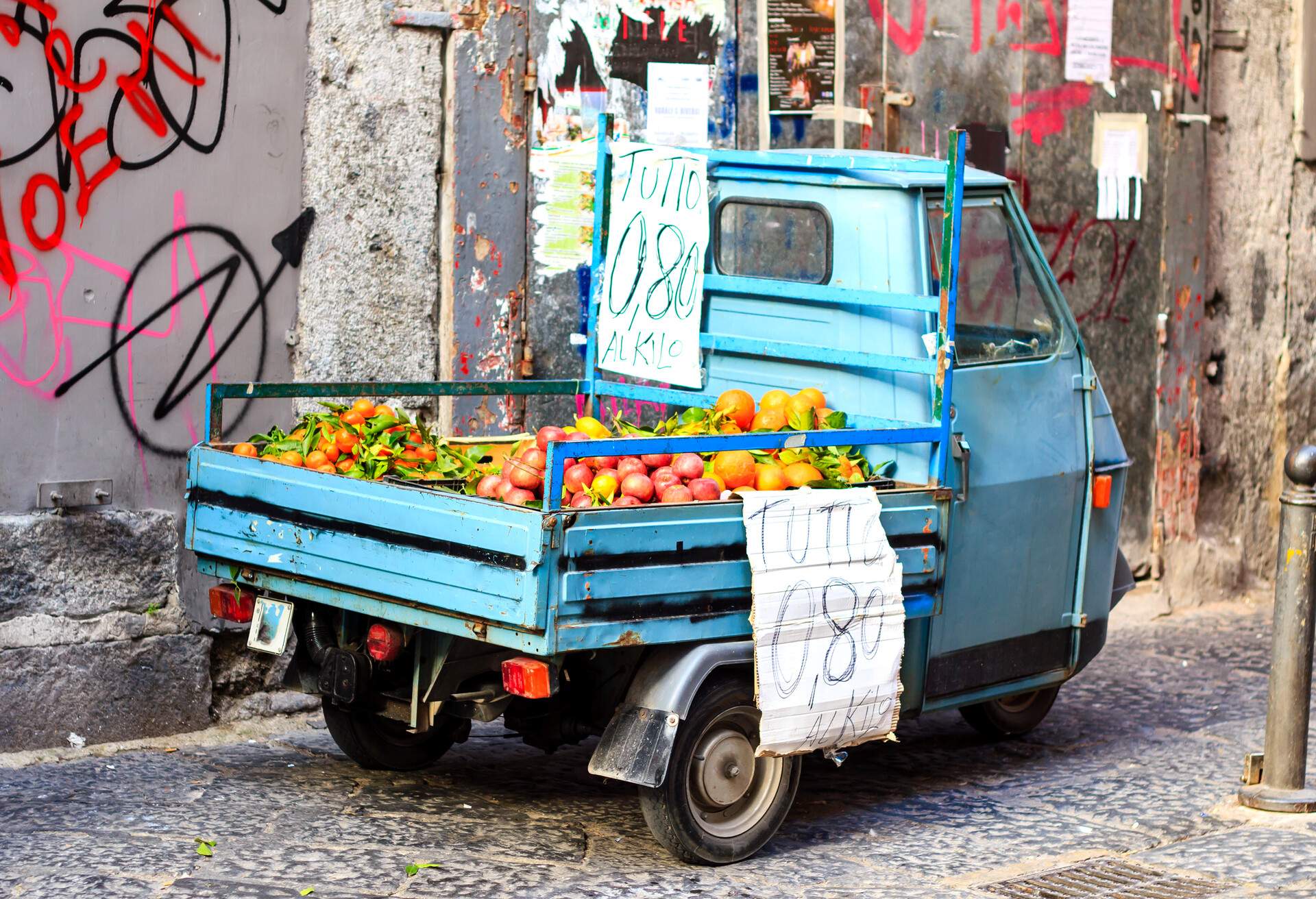 Fruits sold from the old blue mini-truck at the small street of Naples, Italy
