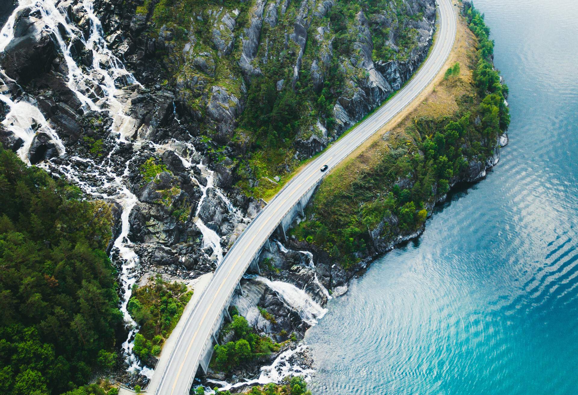 Drone panoramic photo of the car driving through picturesque road above the huge waterfall near the fjord in South Norway