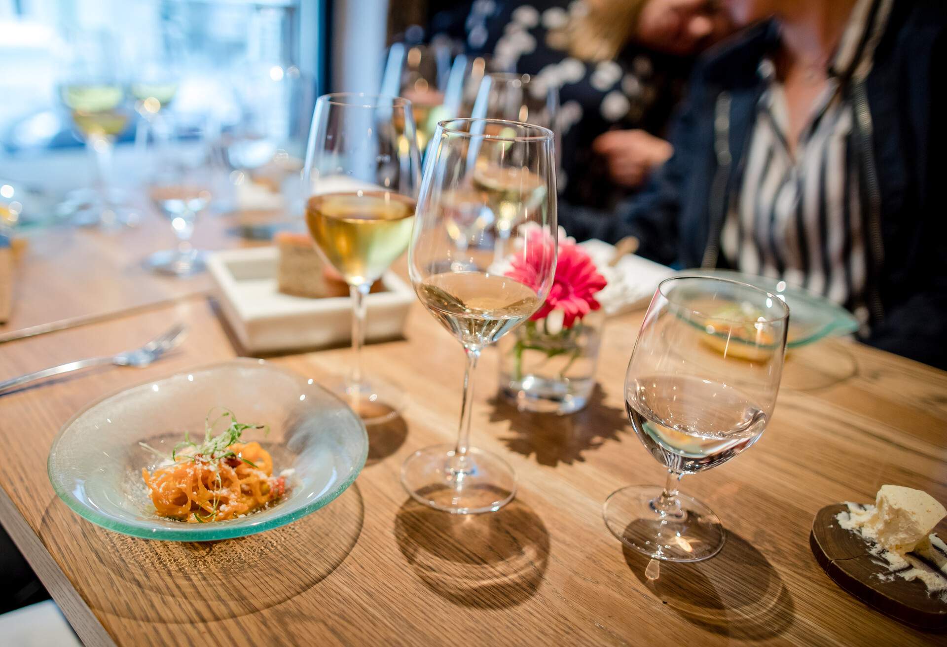 Oslo, Norway - August 23rd, 2018: A well-presented dish rests on a table in a fine dining restaurant in the city of Oslo. Wine and water glasses surround the plate on the table. Fellow diners can be seen out of focus in the background.  Shot on a bright summer evening.