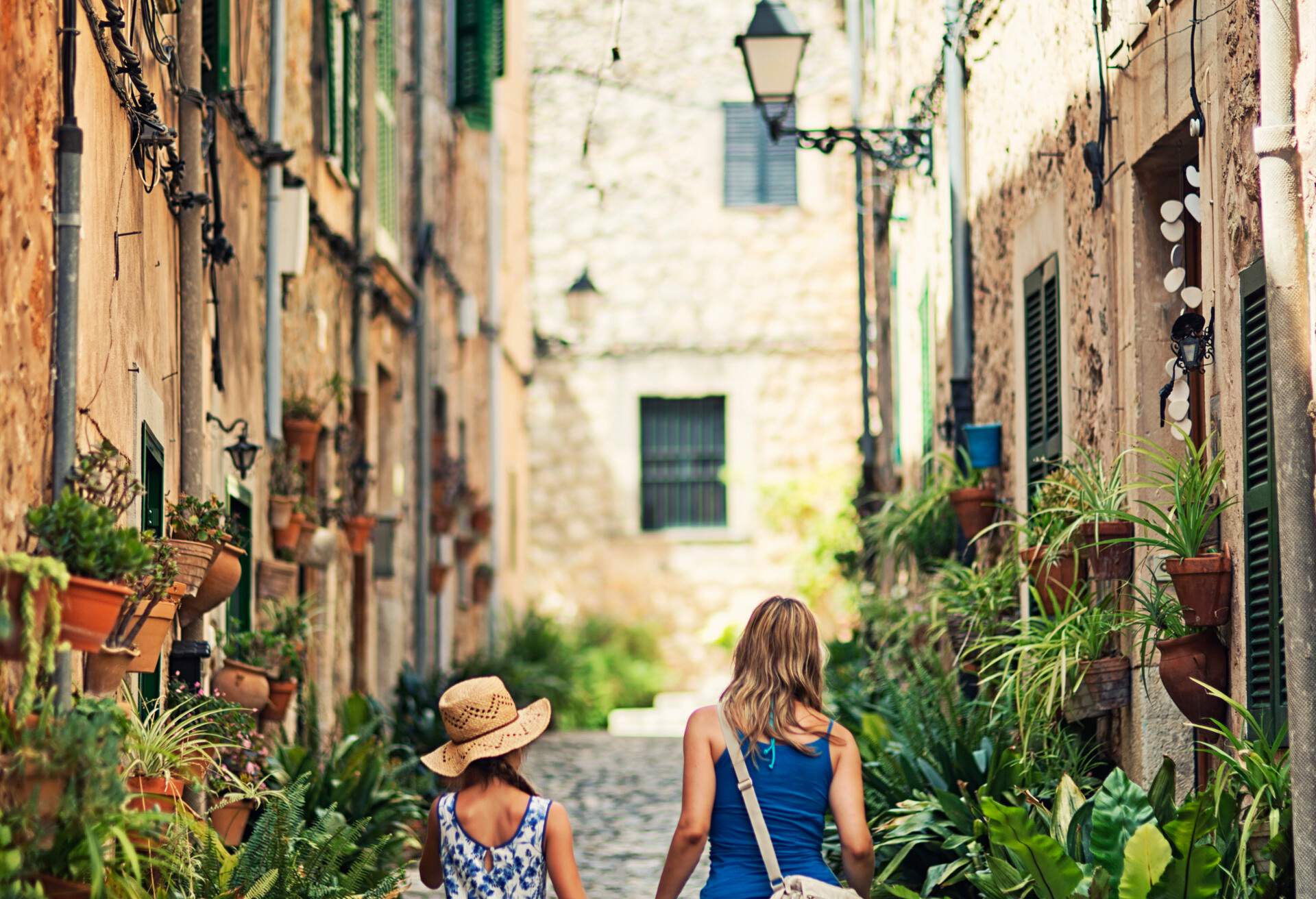 Mother and daughter walking beautiful street of a mediterranean town. Valldemossa, Mallorca, Spain. Slightly soft.