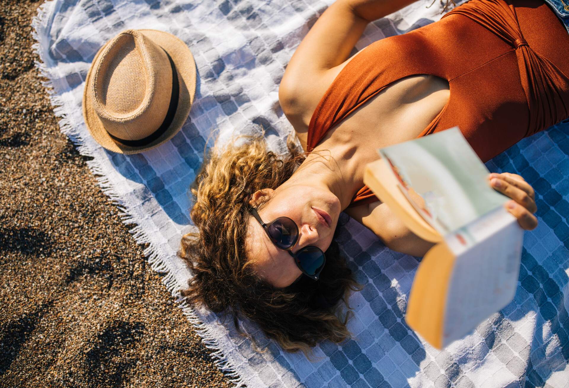 Woman lies on the beach reading a book 