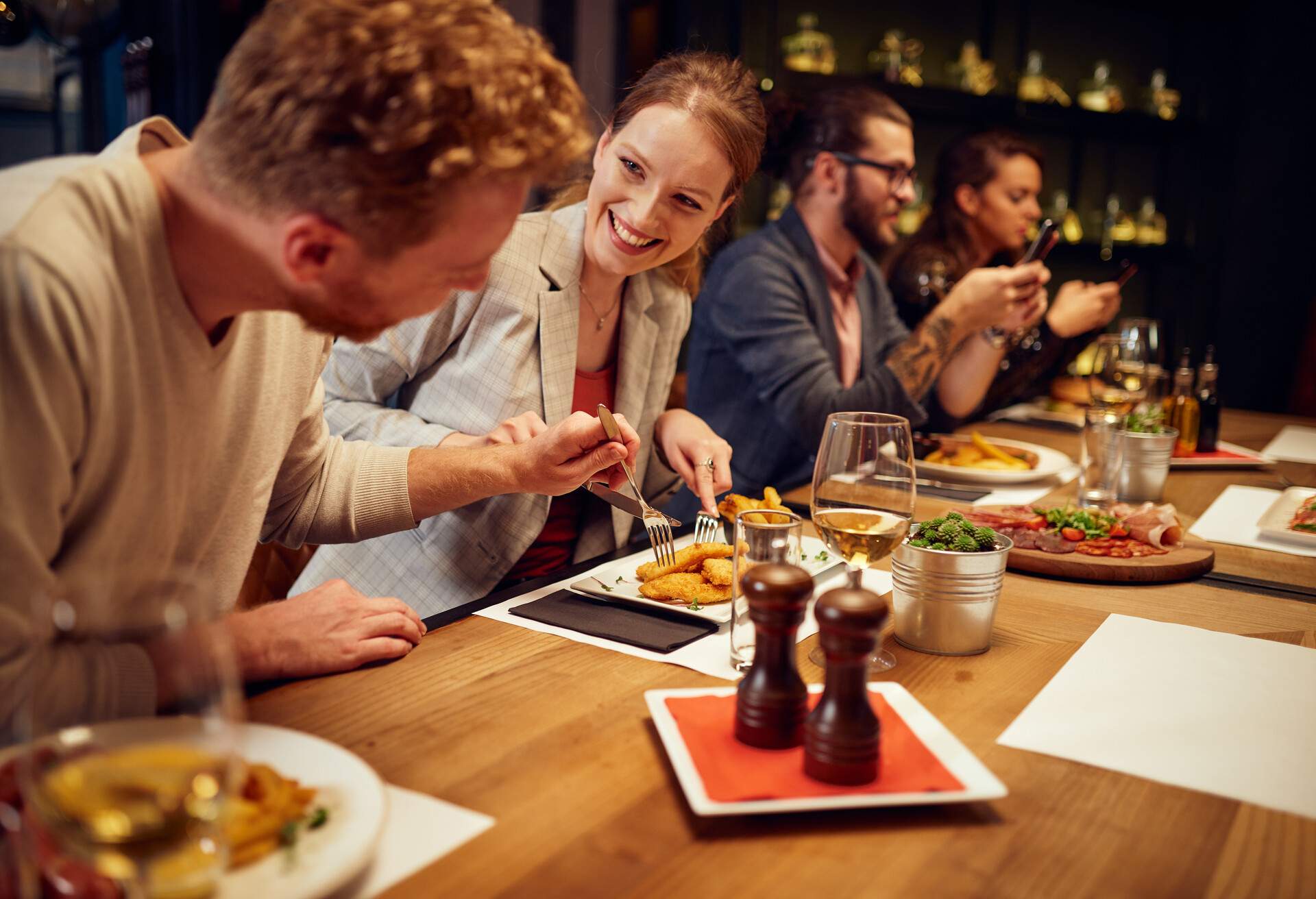 Handsome caucasian ginger taking food out of his girlfriend's plate while sitting in restaurant for dinner. 