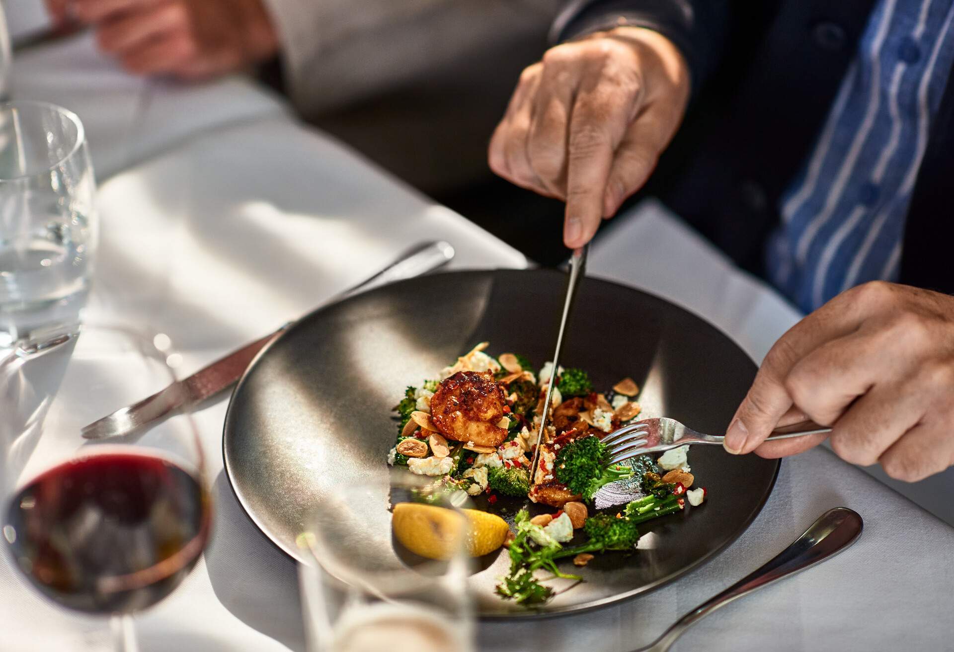 Man cutting food on plate in gourmet restaurant 