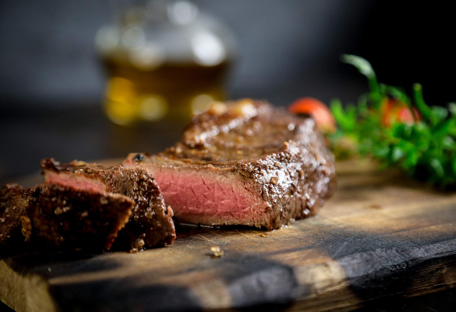 Carne e vegetais grelhados em uma placa de madeira rústica em fundo preto