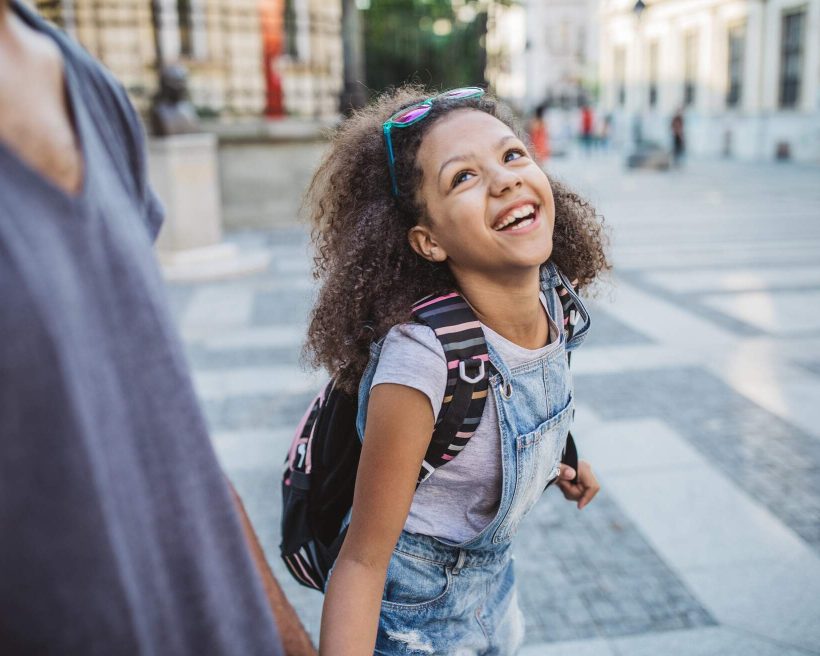 Father bringing daughter to school. Walking the street and holding hands.
