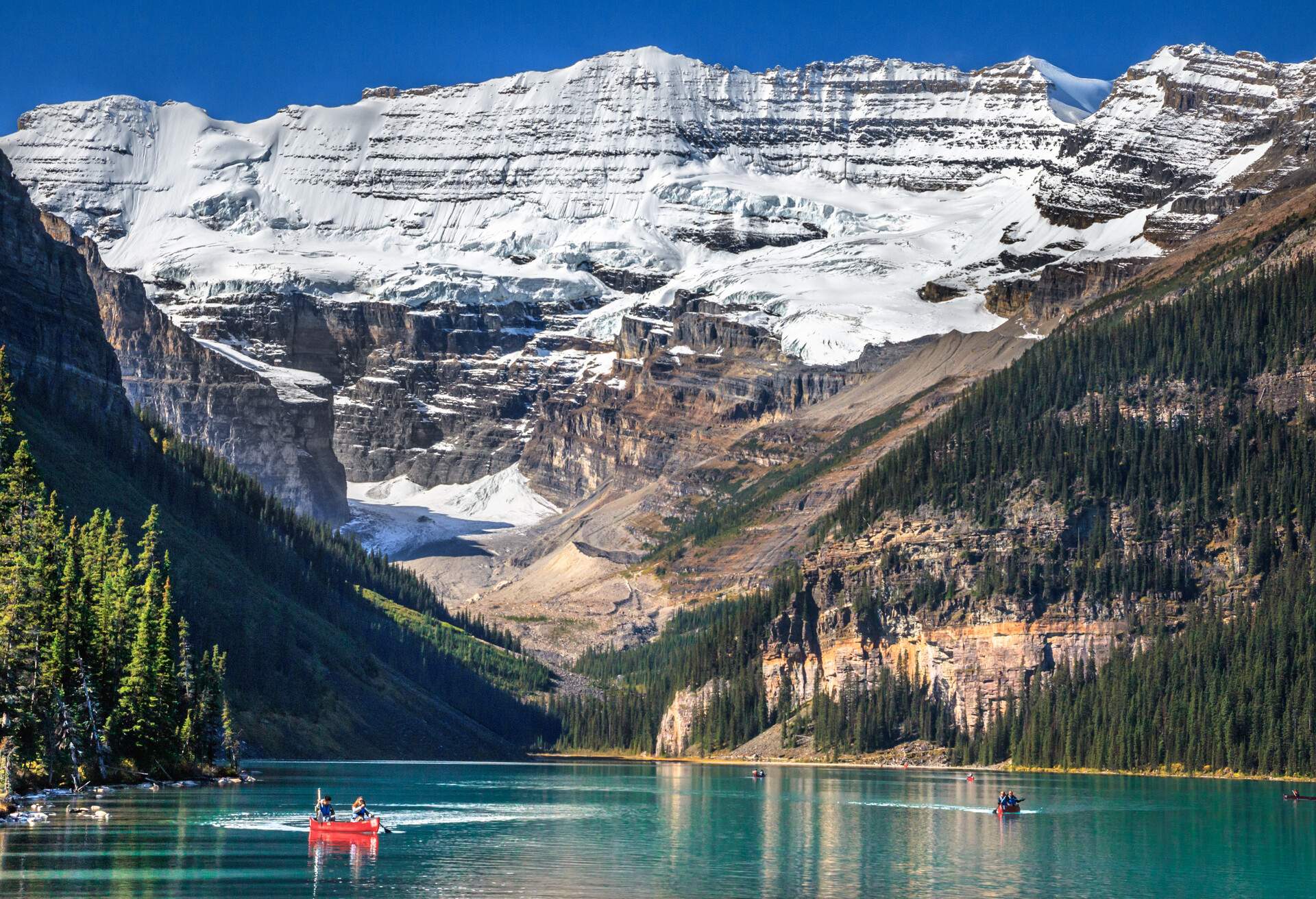 Tourists canoeing at Lake Louise, with Upper Victoria Glacier in background, situated in Banff National Park, Alberta province of Canada.