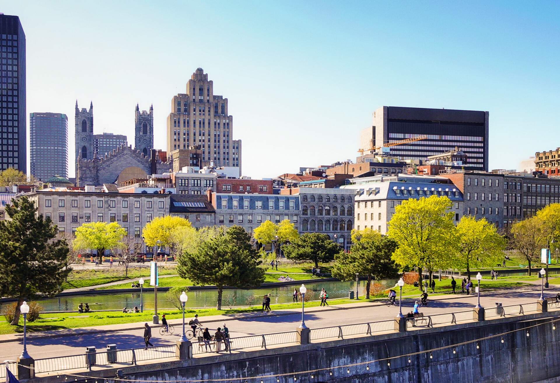 Vieux port de Montreal and downtown skyline with promenade pier on a clear May Springtime day with people walking in the distance