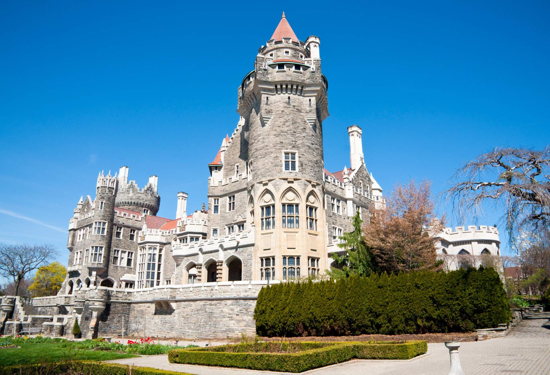 A view of the back of the world-famous Casa Loma in Toronto with the spring gardens just starting and under vibrant blue skies.