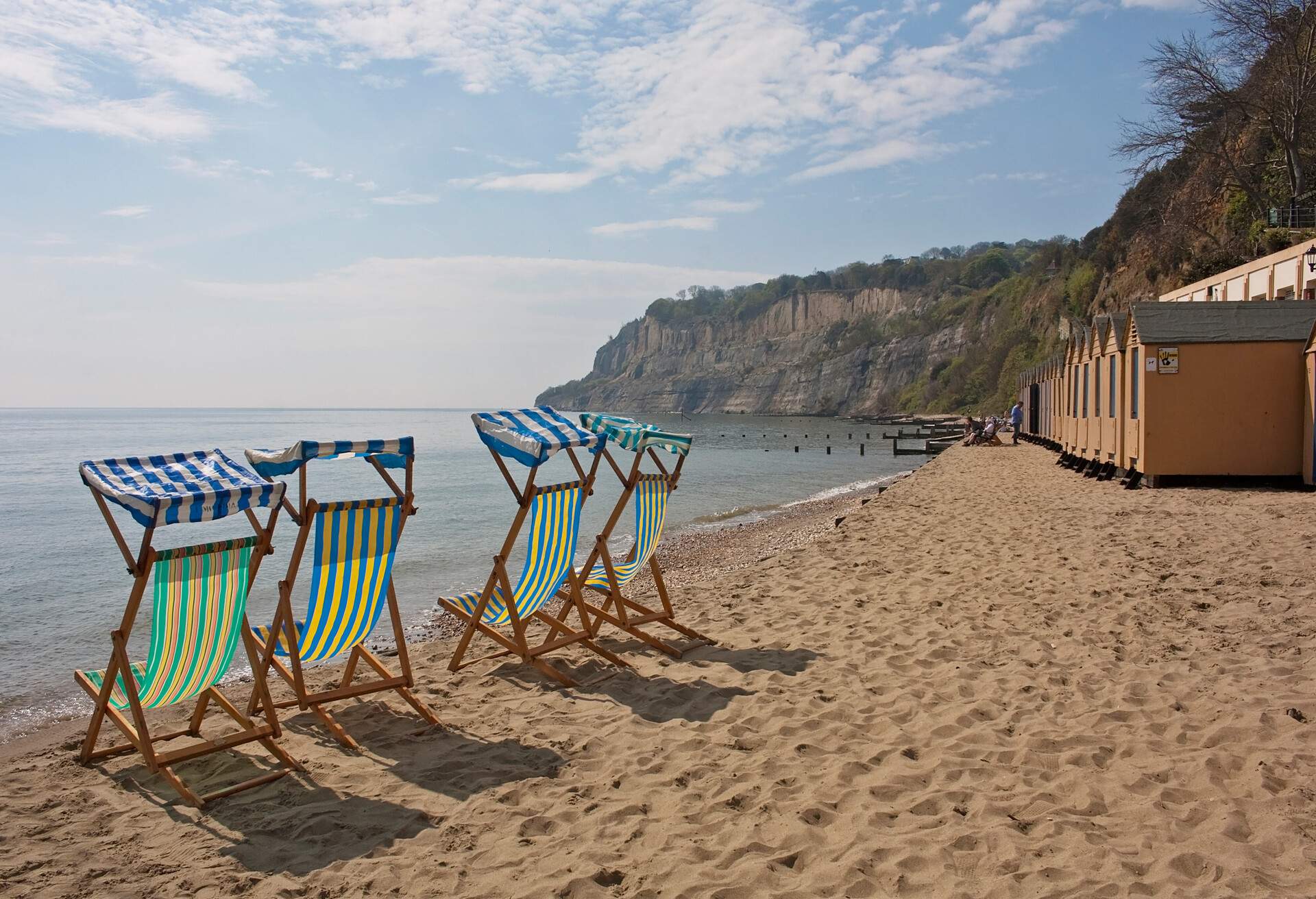 Deck chairs line the beach next to the beach huts on the right at Shanklin in the Isle of Wight