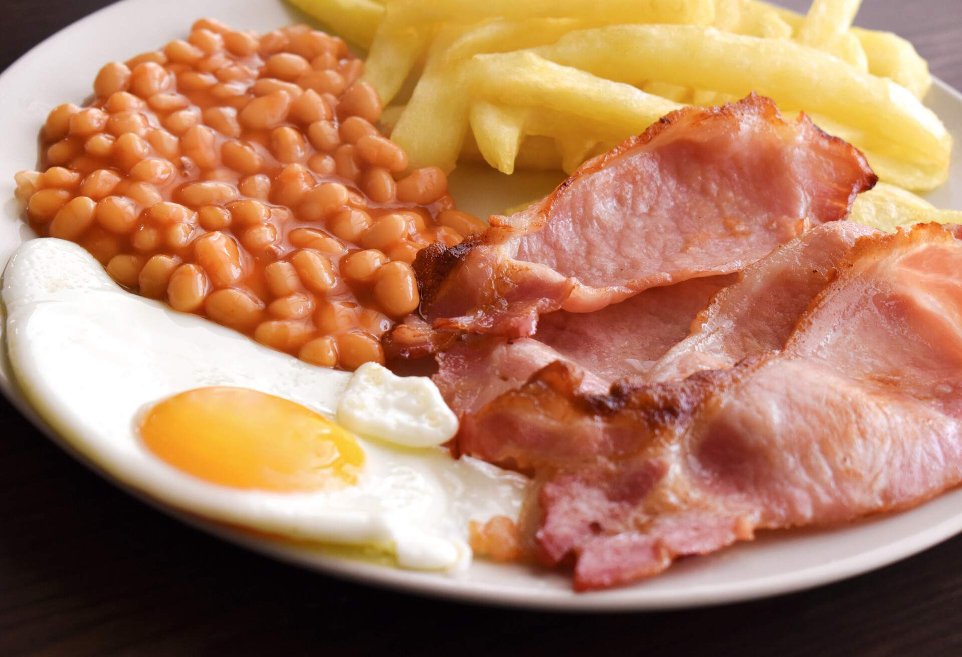 Back bacon, egg, chips and beans on a plate.  English breakfast food style.