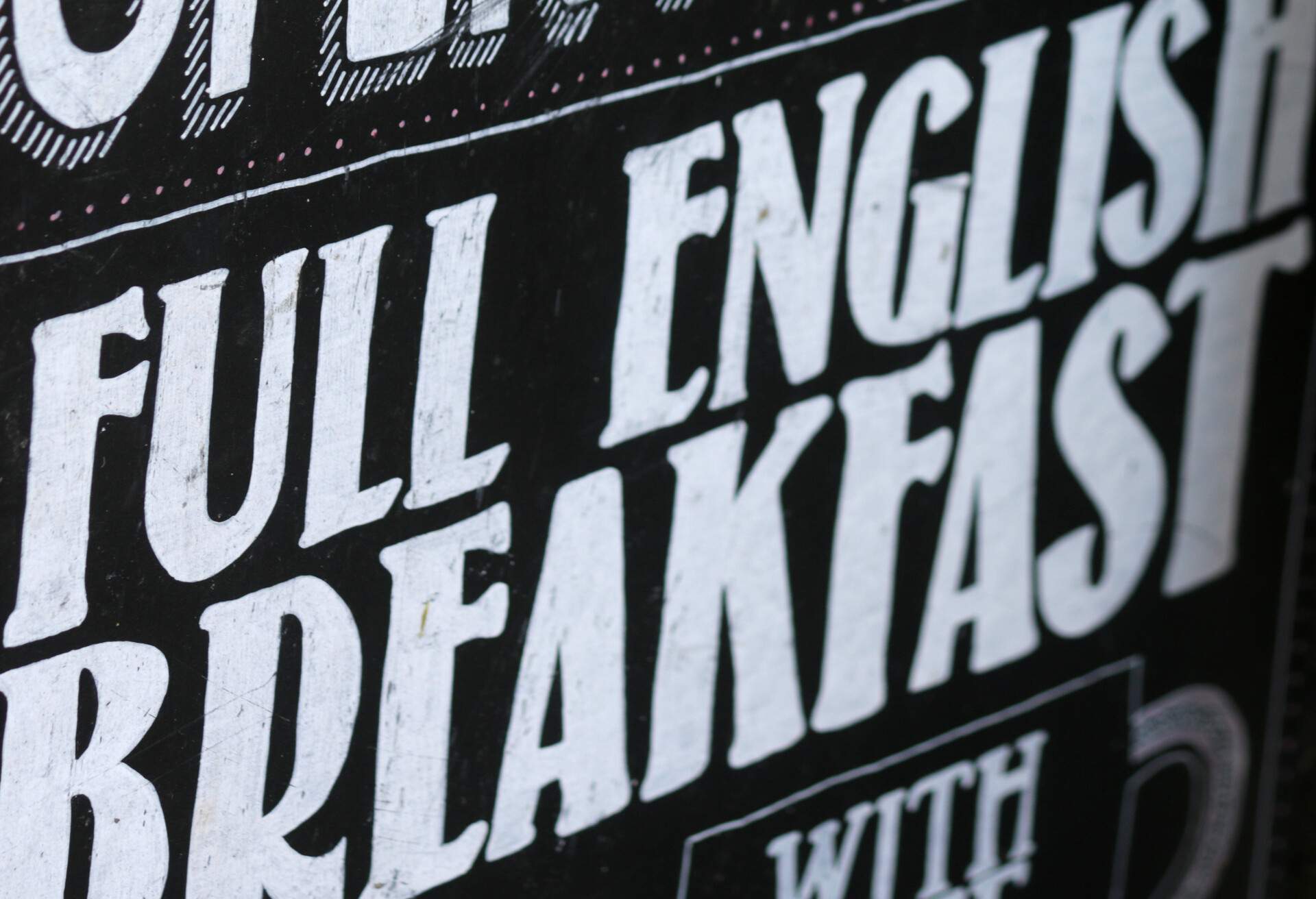 Stock photo of cafe restaurant sign / signpost saying saying full English breakfast on black chalkboard with white writing, selling traditional fried breakfast fry up with sausages and bacon, cup of tea and fried eggs, unhealthy English breakfast food