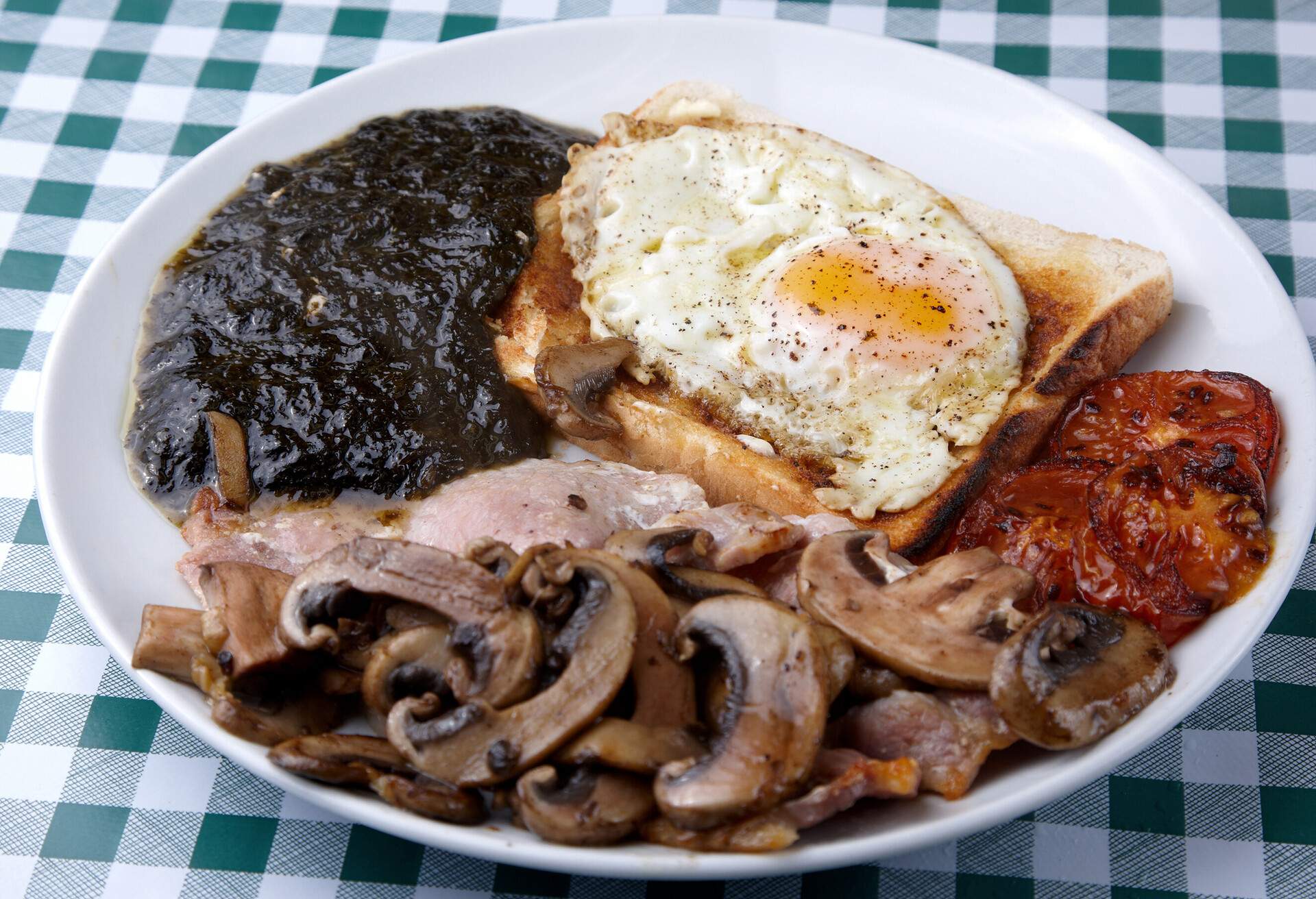 Traditional fried Welsh Breakfast - bacon, mushrooms, fried tomatoes, fried egg, toast and laverbread.