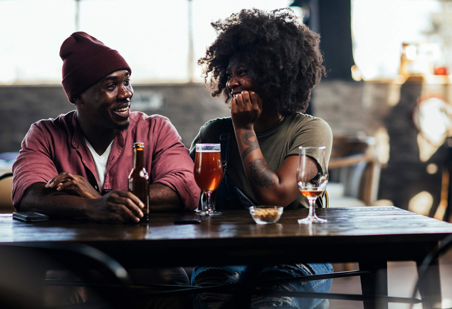 Happy African American couple talking over beers at a bar