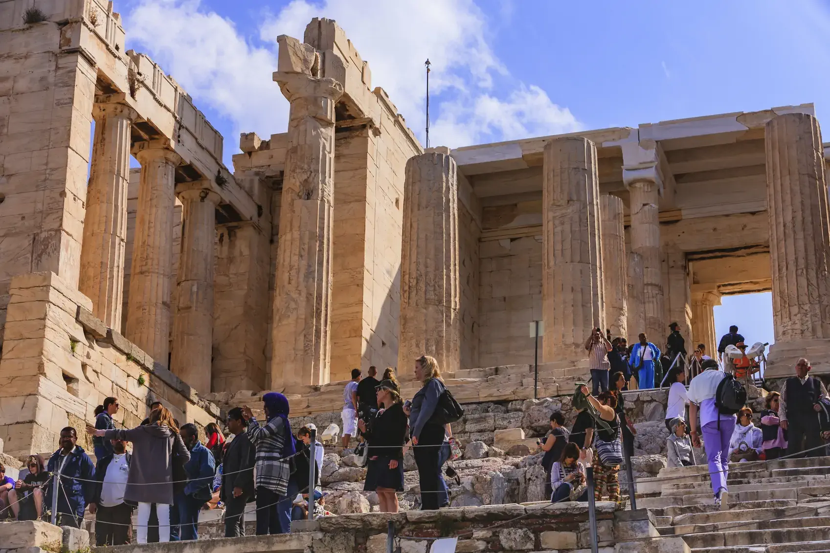 Athens, Greece - April 11, 2010: There are always hordes of tourists at the Acropolis. Photo shows many different groups from several countries; there are caucasians and Africans. They take photos of everything. Photo shot in the morning sunlight; horizontal format. Copy space.