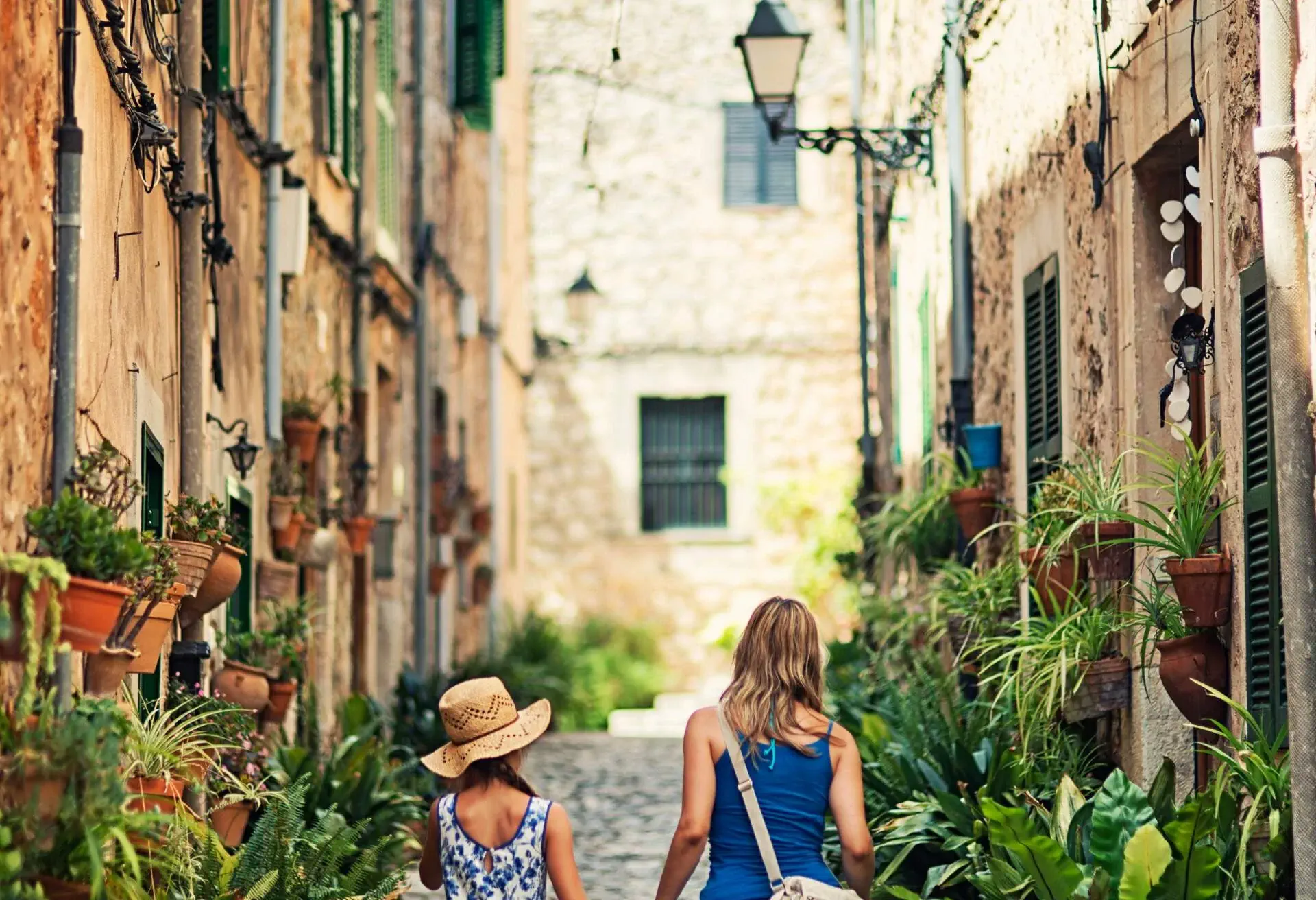 Mother and daughter walking beautiful street of a mediterranean town. Valldemossa, Mallorca, Spain. Slightly soft.
