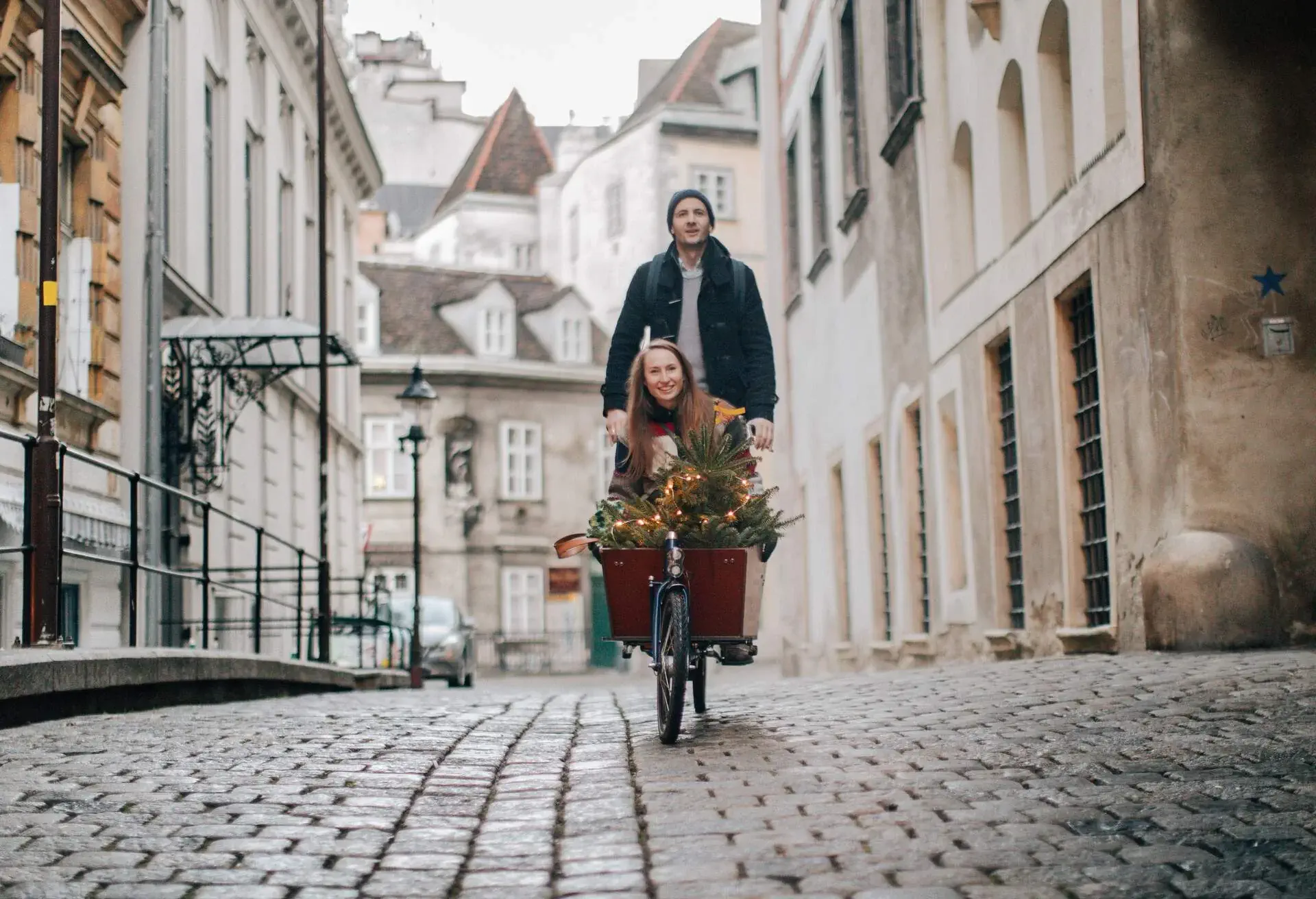 Smiling couple having a fun cargo bike ride while taking their Christmas tree home