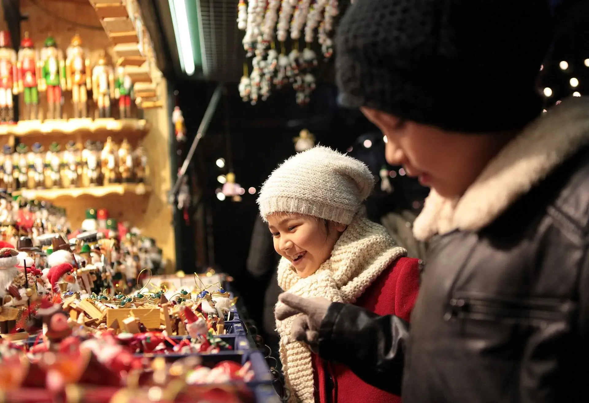 Young boy and girl, siblings, are having fun, chatting and laughing while buying decoration at christmas market.
