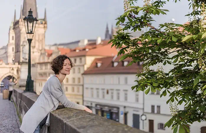 A tourist woman walks along the Charles Bridge in Prague in the summer. Prague, Czech Republic ; Shutterstock ID 1101962888