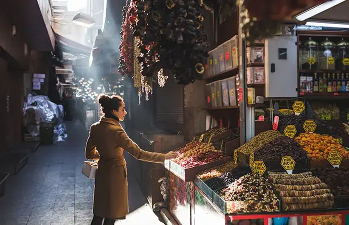 Woman chooses in the market nuts and dried fruit, the buyer tries goods at Grand Bazaar Istanbul; Shutterstock ID 551084959; Purpose: Content; Brand (KAYAK, Momondo, Any): Momondo