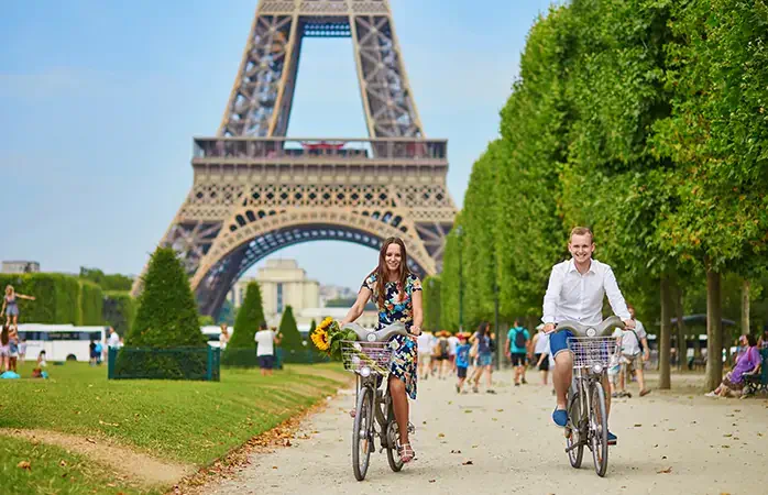Romantic couple riding bicycles near the Eiffel tower in Paris; Shutterstock ID 367875839; Purpose: Content; Brand (KAYAK, Momondo, Any): Momondo