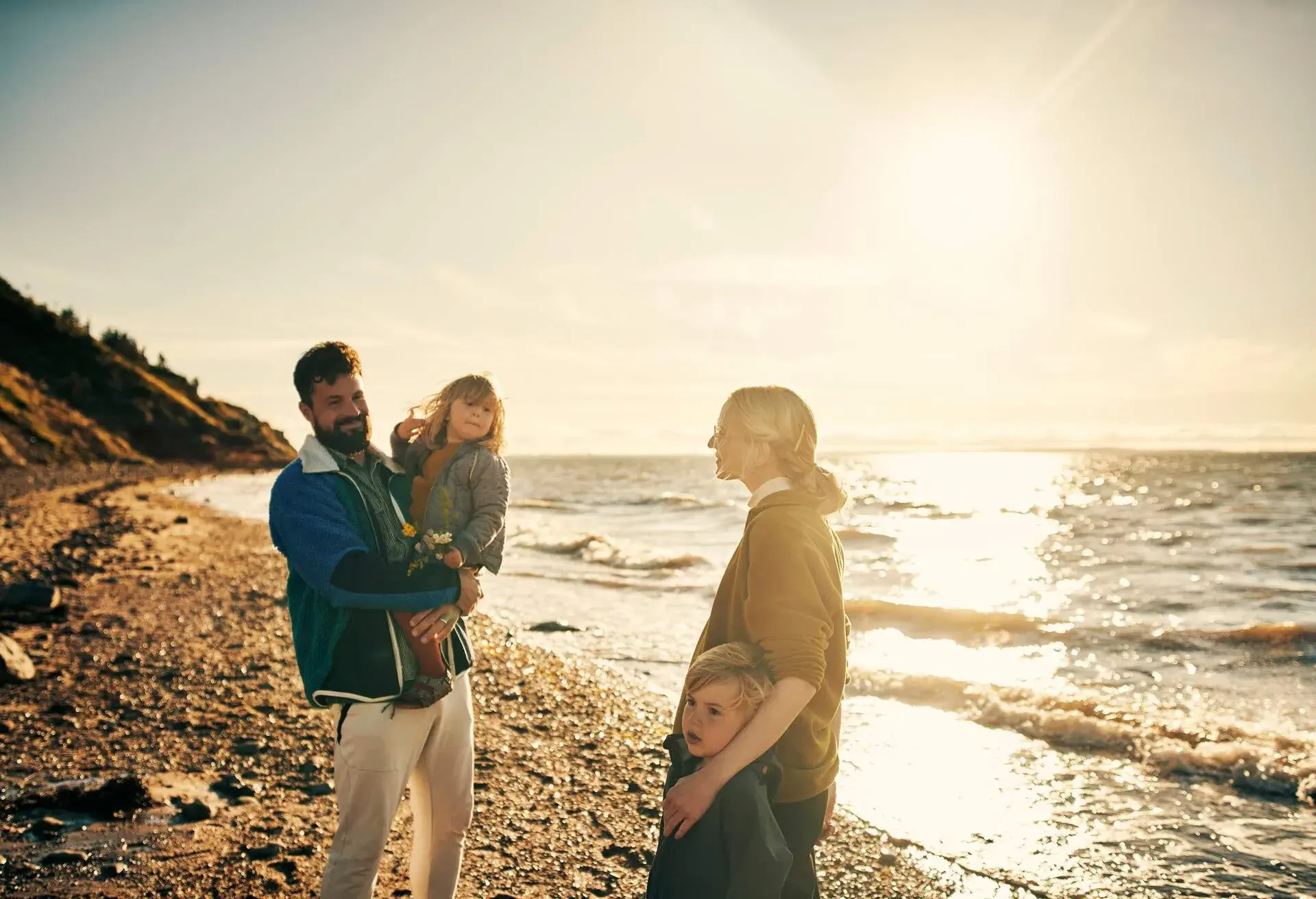 Shot of a young family of four out on the beach together