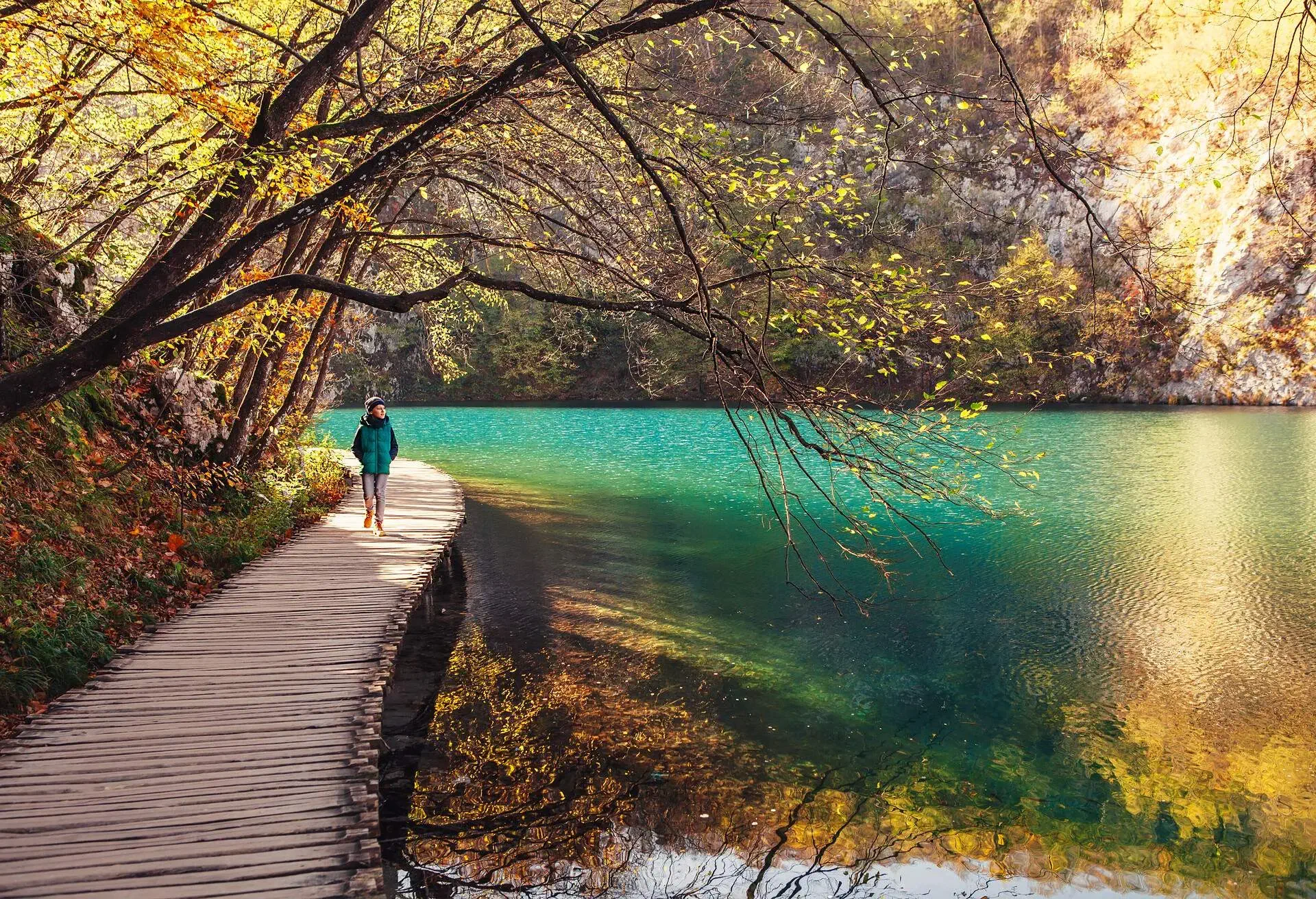Croatia nature park Plitvice Lakes in autumn - boy walks on bridge over the lake