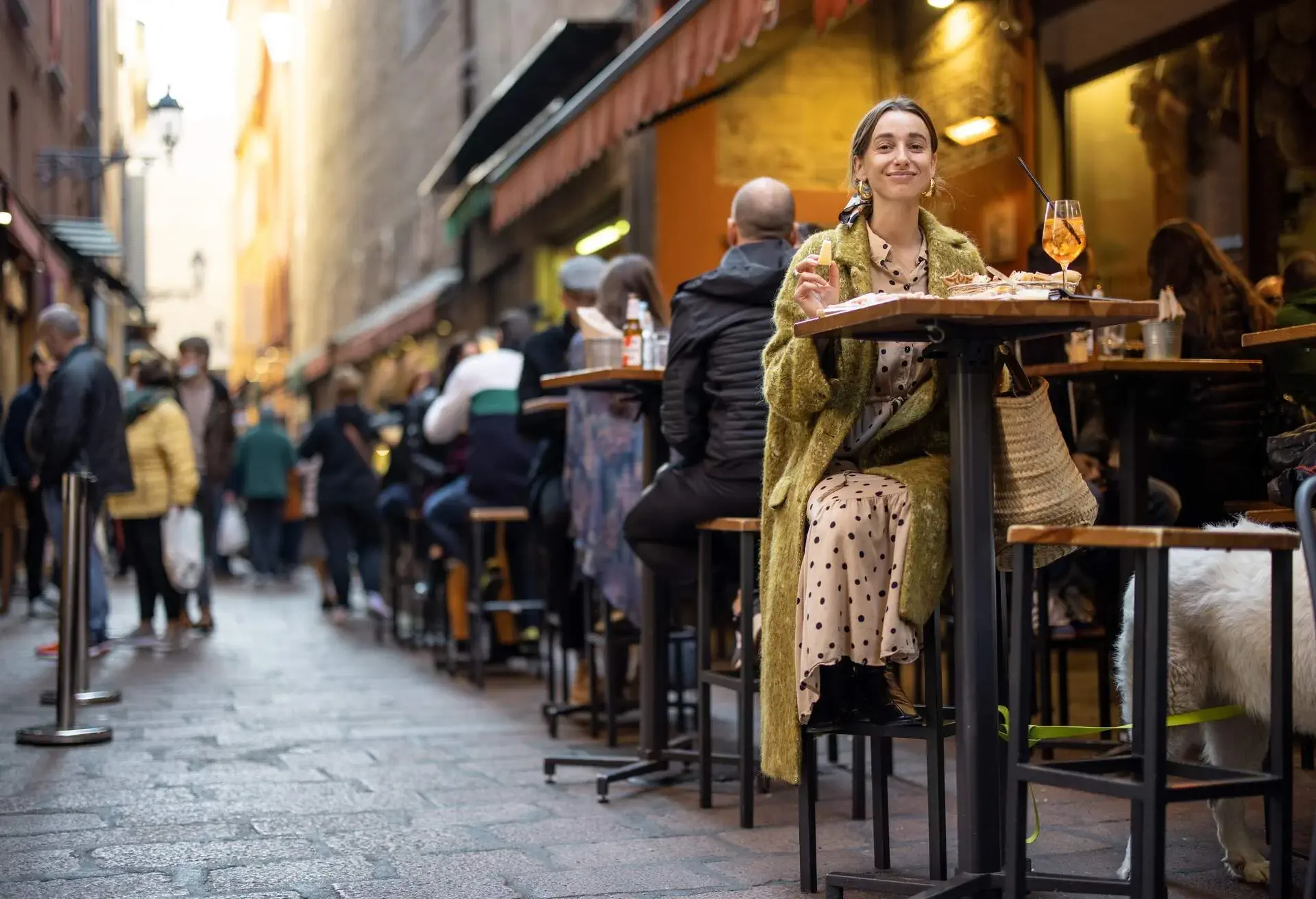 Woman sitting on crowded street at bar or restaurant outdoors in Bologna city. Concept of Italian lifestyle and gastronomy