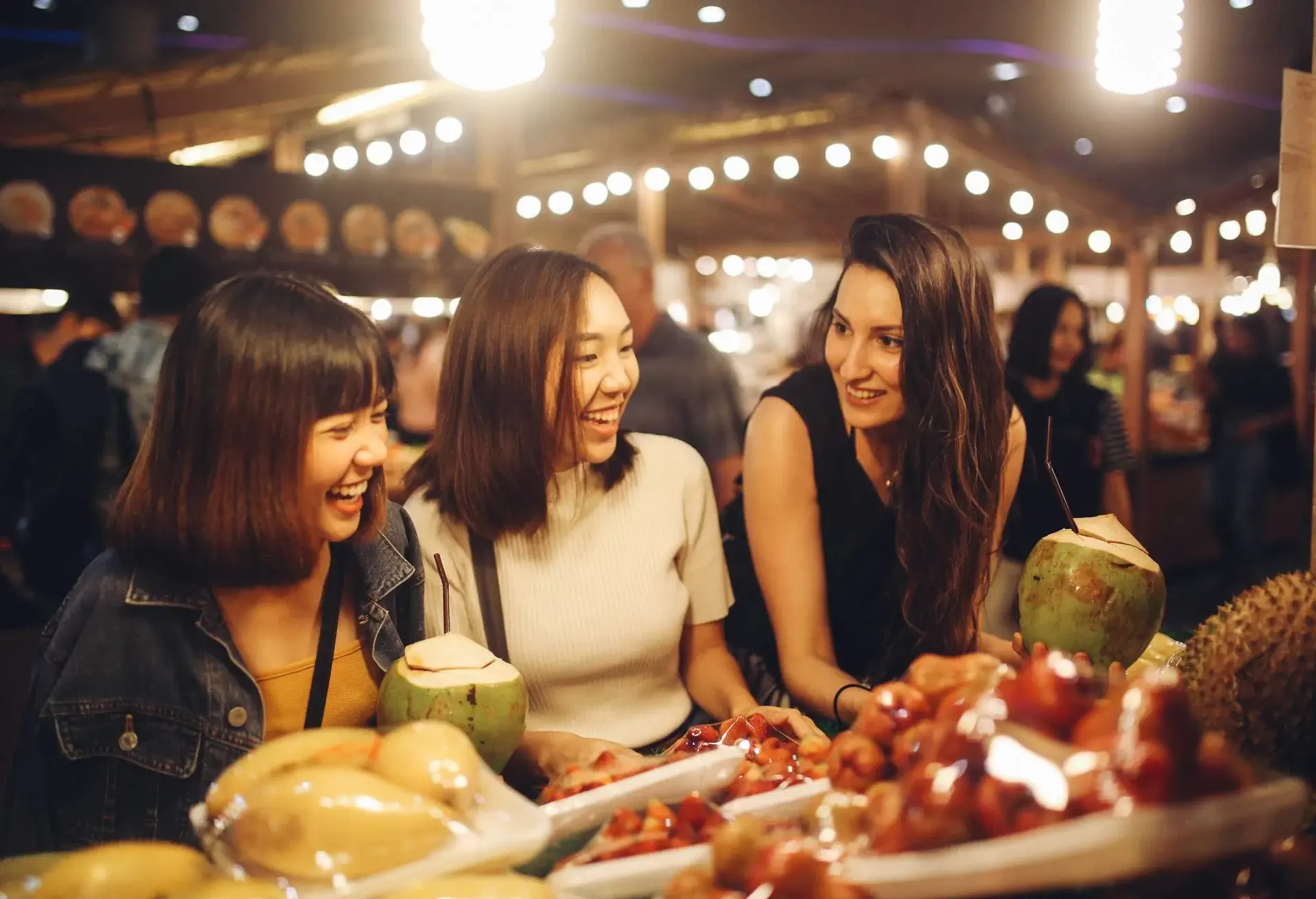 Young girl friends enjoying late night food and shopping in one of the Bangkok's street markets.