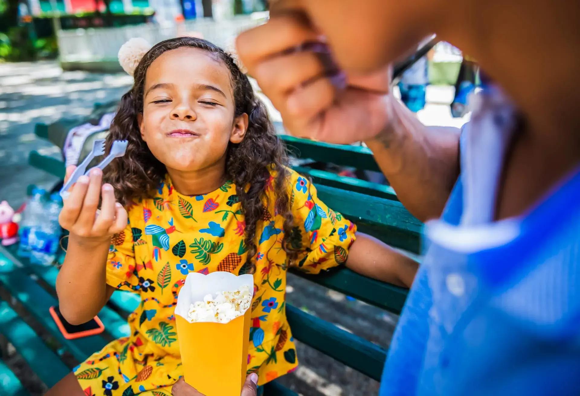 Father and daughter eat popcorn in an amusement park