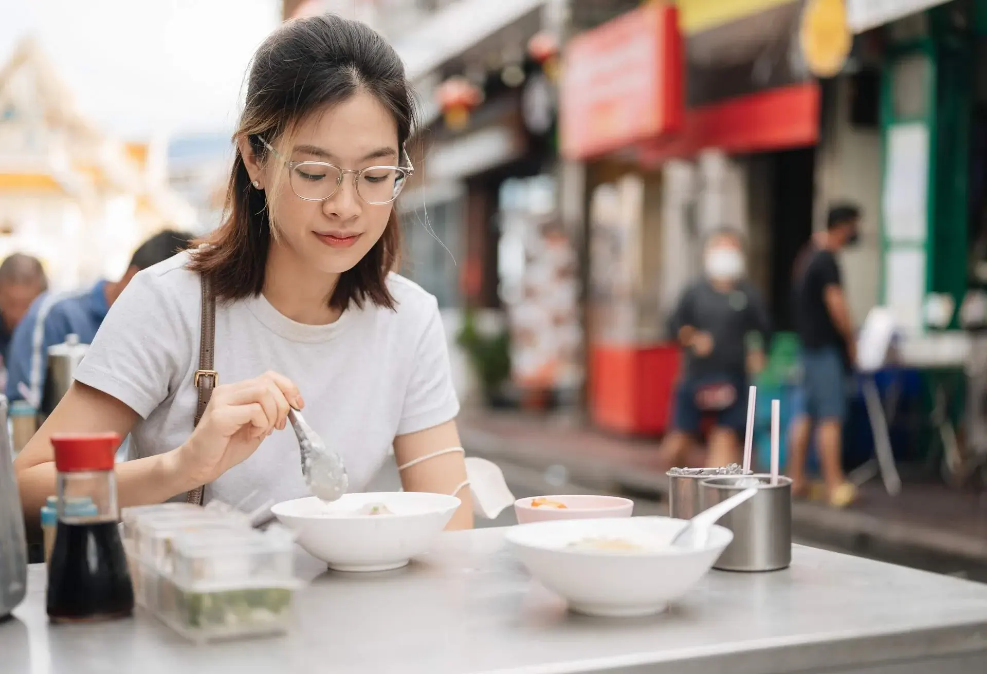 Morning breakfast meal working Young asian female eating rice porridge with tea and Patongo traditional food at street side bangkok thailand