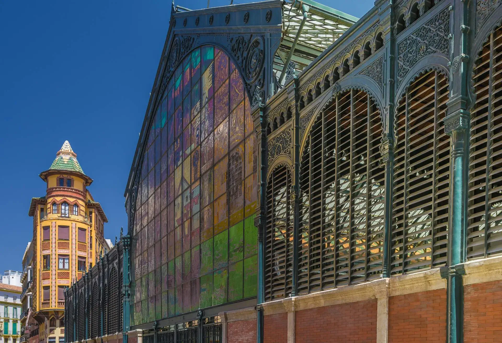 Facade of the Atarazanas food market and Sagasta building in Malaga, Spain on a sunny day.