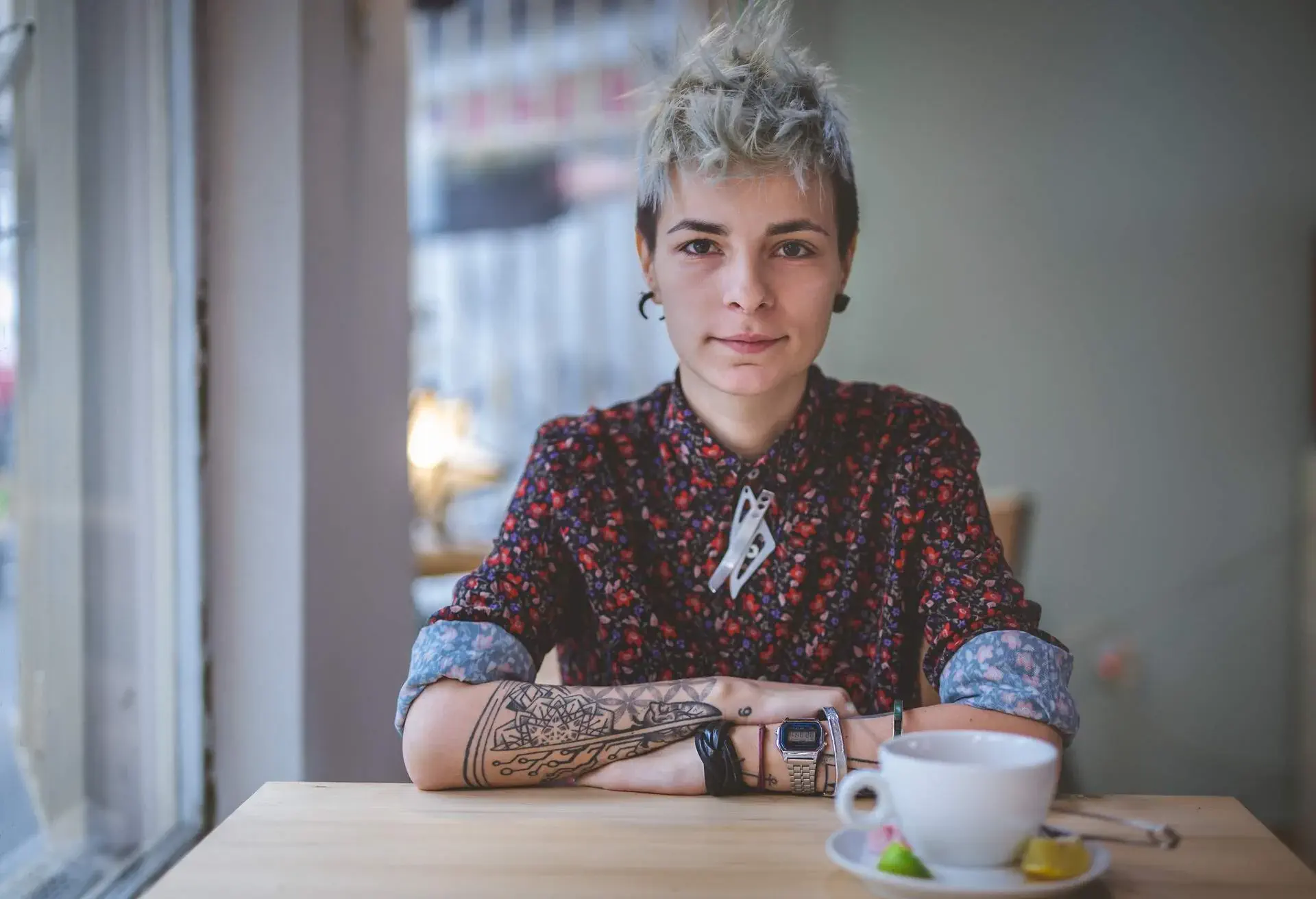 Young and lovely gender blend woman, enjoying a cup of coffee at the cafe.