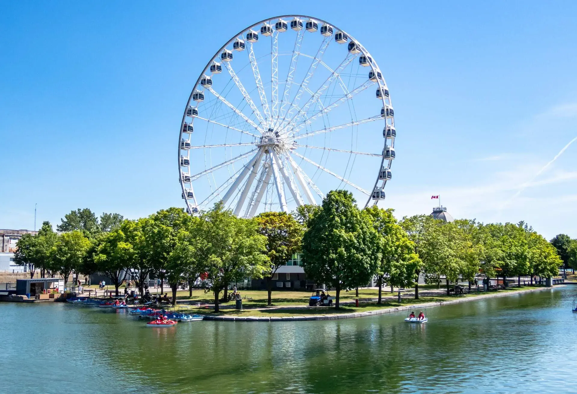 Montreal Ferris wheel in the Old port. La Grande Roue de Montreal. Pedal boats on the river.