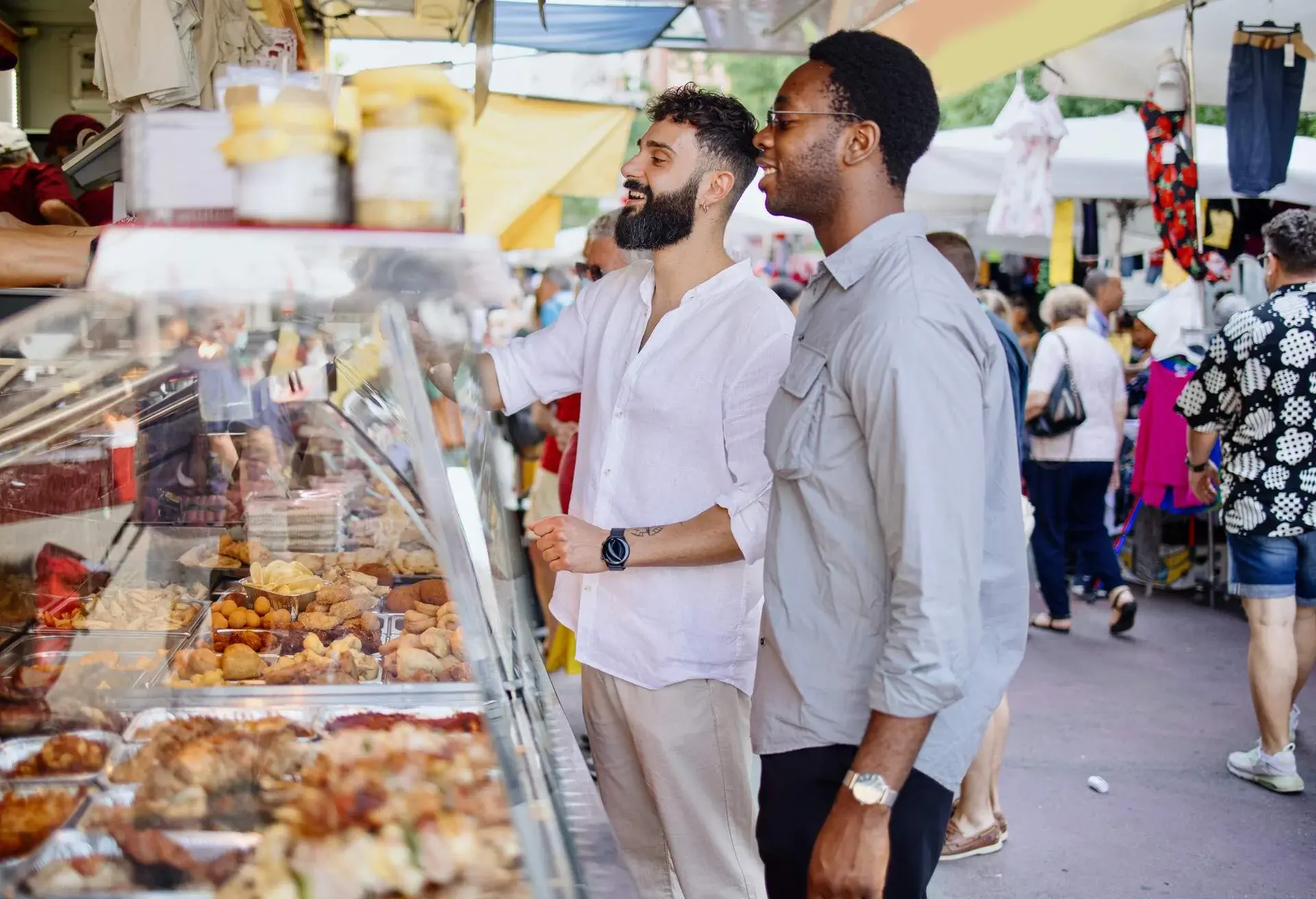 Friends enjoying local cuisine at a food market. Experiential travel concept