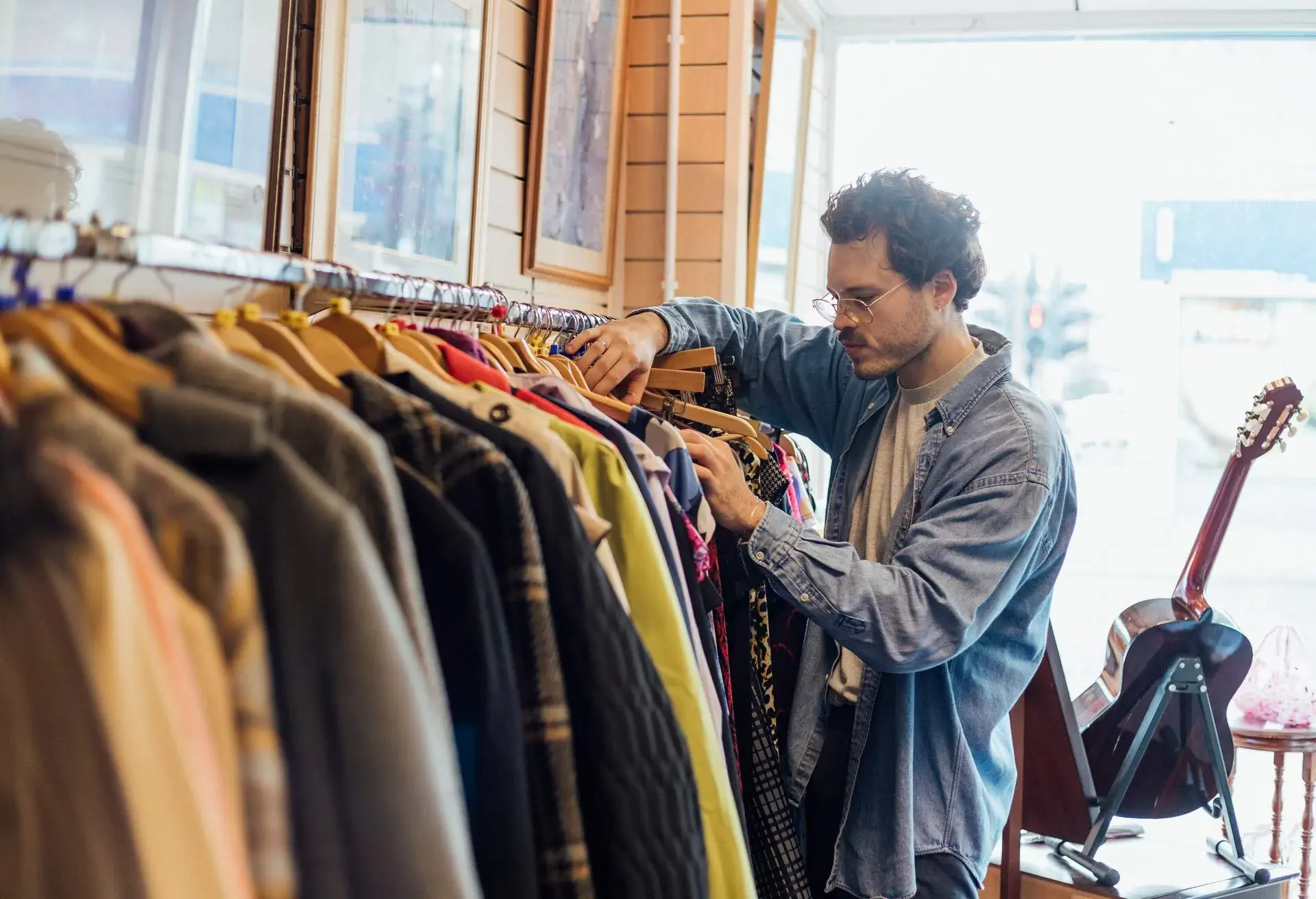 Man looking through clothing while at a thrift store.
